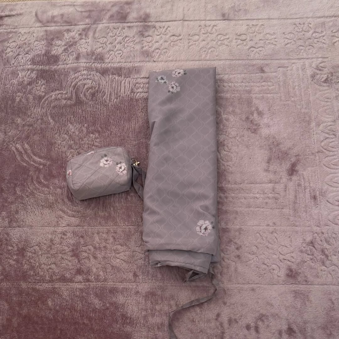 Two-piece prayer dress folded flat next to its matching zip pouch — Maison Haya